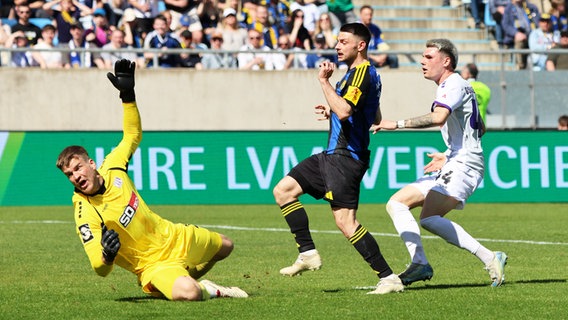 Osnabrücks Torhüter Lukas Jonsson (l.) kann einen Treffer von Saarbrückens Maurice Multhaup (M.) nicht verhindern. © picture alliance / Fußball-News Saarland | Sebastian Bach 