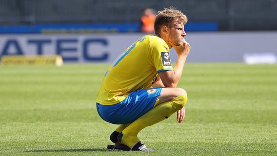Braunschweigs Brian Behrendt hockt auf dem Rasen. © IMAGO / Hübner 