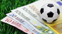 Ein Fußball auf Geldscheinen. Ein Fußball auf Geldscheinen. © picture alliance/Bildagentur-online