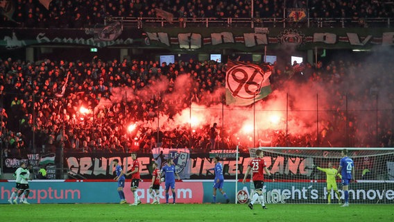 Fans von Hannover 96 zünden Pyrotechnik während des Spiels gegen Magdeburg. © IMAGO / Jan Huebner 