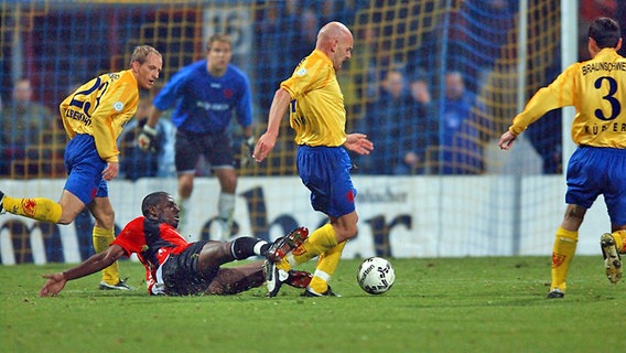 Hannovers Mo Idrissou (unten) grätscht während des Pokalspiels gegen Braunschweig am 29. Oktober 2003, Eintracht-Profi Torsten Lieberknecht (l.). © imago/Garcia 