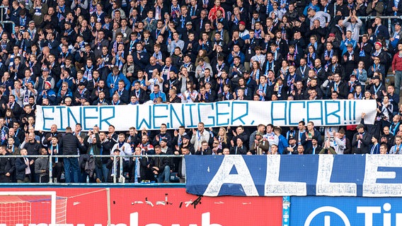 Fans von Hansa Rostock halten ein geschmackloses Plakat in die Höhe © imago images/Fotostand 