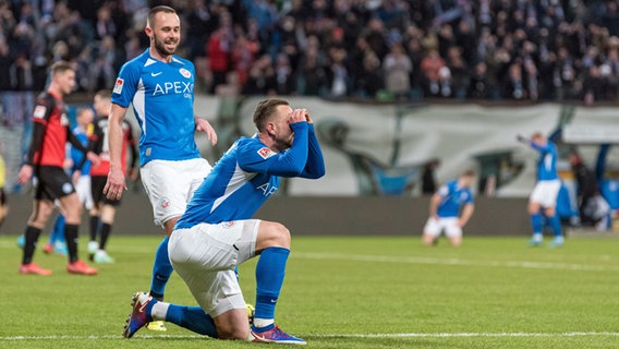 Hansas Pascal Breier (l.) läuft auf John Verhoek zu, der am Boden kniet. © IMAGO / Fotostand 