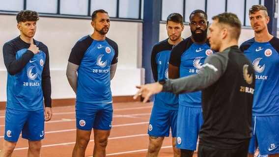 Die Hansa-Spieler Duljevic, Verhoek, Malone, Munsy und Meißner (v.l.n.r.) hören Athletik-Trainer Bornholdt (v.) zu. © Hansa Rostock 