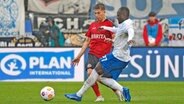 Christian Kinsombi (r.) vom FC Hansa Rostock im Duell mit Nick Bätzner vom SV Wehen Wiesbaden © IMAGO / Jan Huebner 