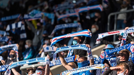 Hansa-Fans mit Maske halten im Stadion ihre Schals hoch. © NDR Foto: picture alliance / Fotostand