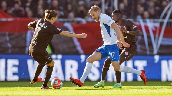 Hansa Rostocks Hanno Behrens (M.) versucht an St. Paulis Jakcson Irvine (l.) vorbeizukommen. © IMAGO / Philipp Szyza 