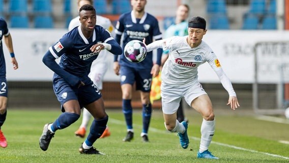 Bochums Armel Bella-Kotschap (l.) im Zweikampf mit Kiels Jae-sung Lee. © IMAGO / Beautiful sports 