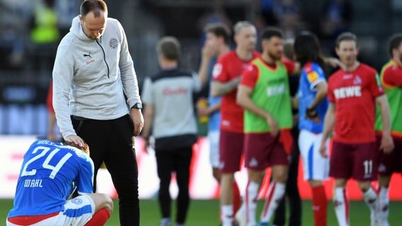 Trainer Ole Werner tröstet den Kieler Kapitän Hauke Wahl (l.), der enttäuscht am Boden hockt. © dpa-Bildfunk 