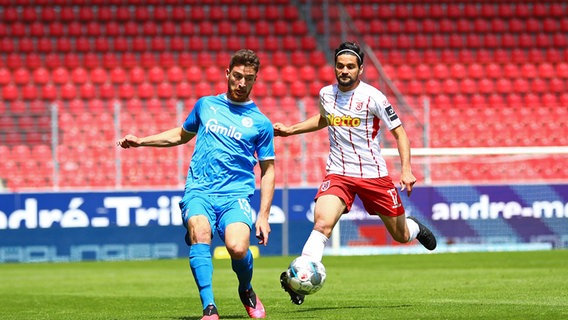 Kiels Salih Özcan (l.) behauptet den Ball vor Regensburgs Oliver Hein. © imago images / Poolfoto 