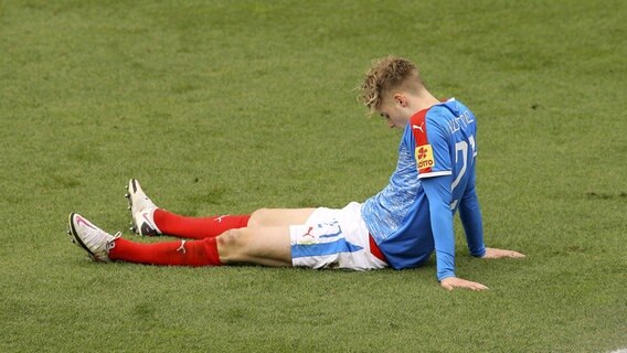 Kiels Fußballer Fin Porath sitzt enttäuscht auf dem Rasen. © IMAGO / Claus Bergmann 