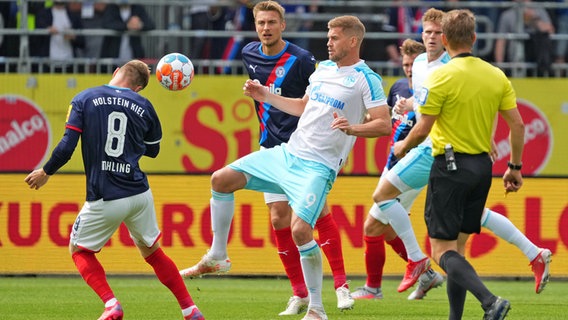 Schalkes Stürmer Simon Terodde (M.) behauptet den Ball gegen die Kieler Alexander Mühling (l.) und Hauke Wahl (2.v.l.). © Witters 
