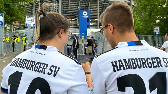 Zwei HSV-Fans schauen das Spiel vor dem Volksparkstadion auf dem Handy. © NDR 