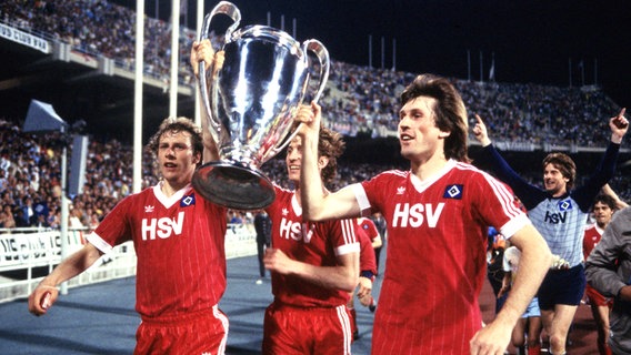 Wolfgang Rolff (l.), Ditmar Jakobs und Manfred Kaltz bejubeln mit dem Pokal den Sieg des HSV im Europacup der Landesmeister 1983. © Witters 