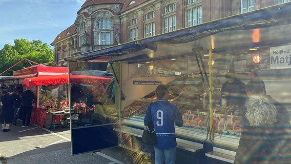 Ein Mann mit einem HSV-Trikot vor einem Fischstand am Hamburger Rotherbaum Ein Mann mit einem HSV-Trikot vor einem Fischstand am Hamburger Rotherbaum © NDR / Nils Kinkel