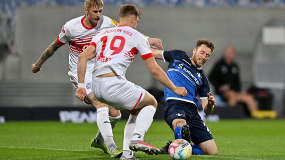 Marvin Schulz (Holstein Kiel, l.) und Simon Lorenz (Holstein Kiel, Mitte) gegen Matthias Bader (SV Darmstadt 98) © Imago/JanHuebner 