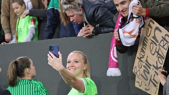 Turid Knaak vom VfL Wolfsburg macht nach dem Champions-League-Halbfinale gegen den FC Barcelona ein Selfie mit Fans. © IMAGO / Hübner 