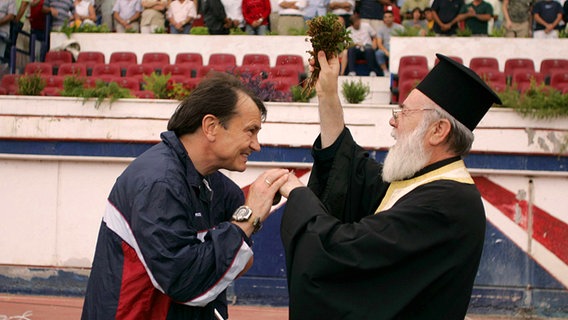 Ewald Lienen bei Panionios Athen mit griechisch orthodoxem Priester © imago/ANE 