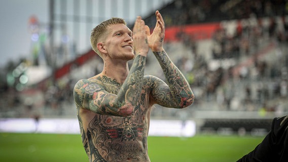 Simon Makienok applaudiert den Fans im Millerntorstadion mit freiem, komplett tätowierten Oberkörper. © IMAGO / Beautiful Sports 