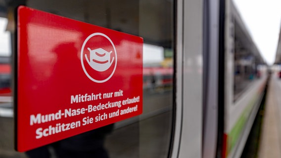 Ein Schild mit der Aufschrift "Mitfahrt nur mit Mund-Nase-Bedeckung erlaubt! Schützen Sie sich und andere!" klebt an der Tür eines Fernzugs der Deutschen Bahn. © picture alliance/dpa Foto: Daniel Karmann