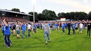 Fans des SV Meppen feiern den Drittliga-Aufstieg auf dem Rasen. © imago/osnapix 