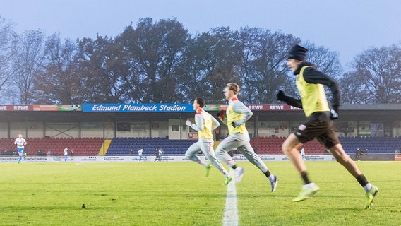 Fußballspieler laufen über den Rasen des Edmund-Plambeck-Stadions in Norderstedt © IMAGO / R.Seidel Imagery 
