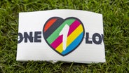 Eine Binde mit der Aufschrift "One Love" liegt auf dem Rasen © IMAGO / Pro Shots 