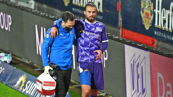 Angreifer Christian Santos (r.) vom VfL Osnabrück wird von Physiotherapeut Lennart Bartling vom Platz begleitet © imago images / Nordphoto 