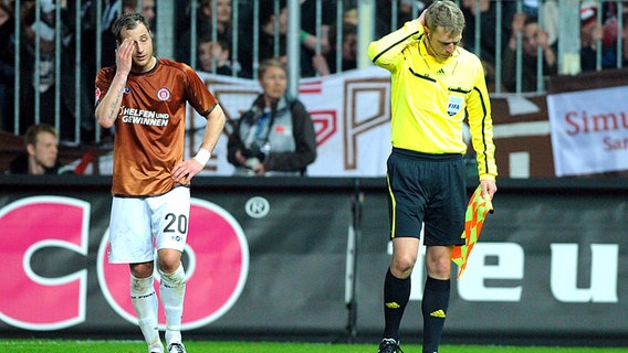 Linienrichter Thorsten Schiffner (r.) fasst sich neben St. Paulis Matthias Lehmann an den Kopf. © dpa 