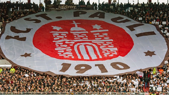 Fans des FC St. Pauli zeigen ein großes Banner mit dem Vereins-Wappen. © imago images / Focus Images 