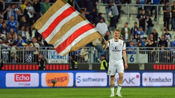 St.-Pauli-Profi David Otto schwenkt eine St.-Pauli-Fahne. © IMAGO / Jan Huebner 