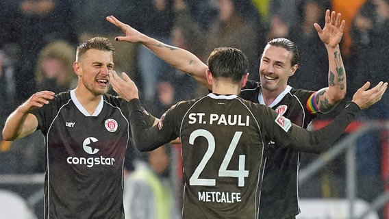 St. Paulis Spieler Hauke Wahl (l.), Connor Metcalfe (Mitte) und Jackson Irvine freuen sich. © picture alliance / DPA 