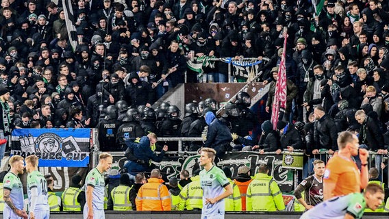 Polizisten werden im Millerntorstadion aus dem Gästeblock mit Stangen und Bechern beworfen, setzen in Folge dessen Reizgas ein. © IMAGO / Oliver Ruhnke 