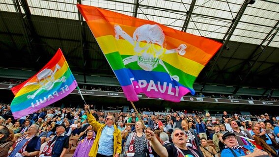 Fans des FC St. Pauli schwenken Regenbogenfahnen. © IMAGO/Oliver Ruhnke 