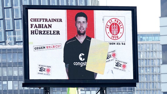 Die Anzeigetafel am Millerntor zeigt die Gelbe Karte für Trainer Fabian Hürzeler an. © IMAGO/Eibner 