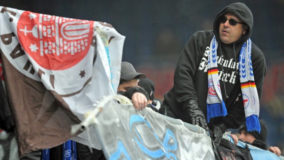 Ein Fan von Hansa Rostock, vor ihm eine gestohlene Fahne des FC St. Pauli © Witters Foto: Tim Groothius