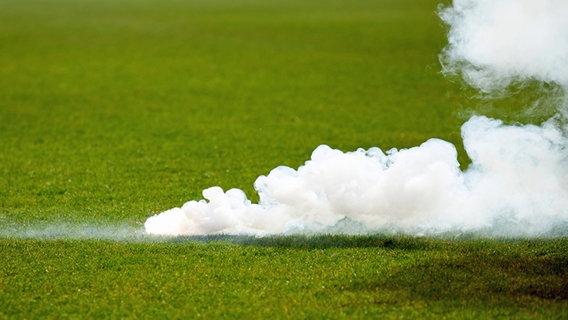 Ein rauchender Bengalo liegt auf dem Rasen im Eintracht-Stadion. © IMAGO / Eibner 