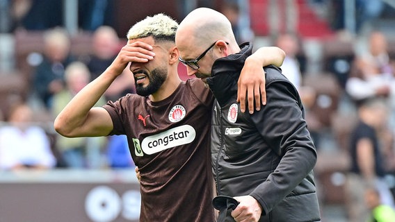 Elias Saad (l.) vom FC St. Pauli wird verletzt von Platz begleitet © Witters 