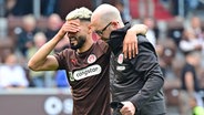 Elias Saad (l.) vom FC St. Pauli wird verletzt von Platz begleitet © Witters 