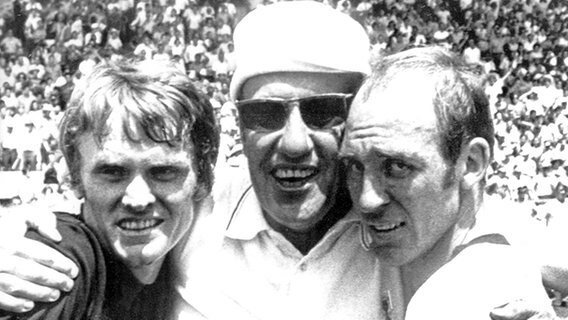 Bundestrainer Helmut Schön (M.) umarmt 1970 Torhüter Sepp Maier (l.) und Abwehrspieler Willi Schulz (r). © picture-alliance/ dpa 