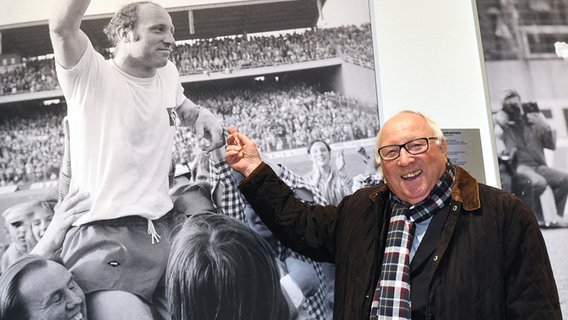 Uwe Seeler zeigt auf ein Foto von sich in jungen Jahren. © Witters 