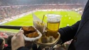 Ein Fußball-Fan hat Hähnchen, Pommes und Bier in der Hand. © imago / ActionPictures 