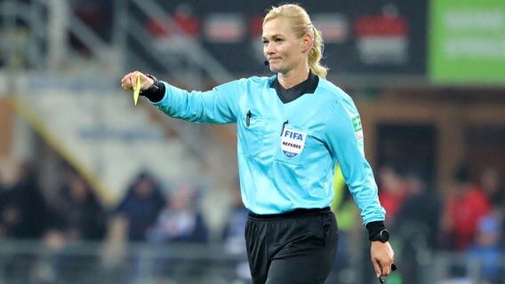 Schiedsrichterin Bibiana Steinhaus hält eine Gelbe Karte in der Hand. © Imago Images 