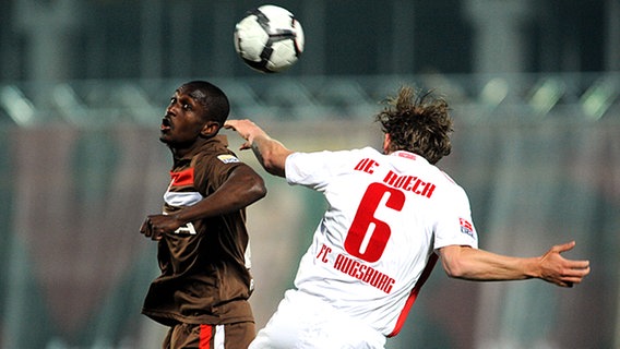 St. Paulis Charles Takyi (l.) gewinnt den Kopfball gegen Jonas de Roeck vom FC Augsburg. © dpa 