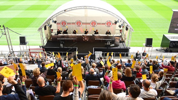 Bei der Mitgliederversammlung des FC St. Pauli heben die Mitglieder im Millerntorstadion in Abstimmungskarten. © Witters Foto: Tay Duc Lam