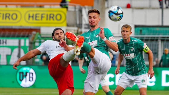 Sören Reddemann vom VfB Lübeck (M.) im Zweikampf mit Halles Dominic Baumann © IMAGO/nordphoto Foto: Tauchnitz