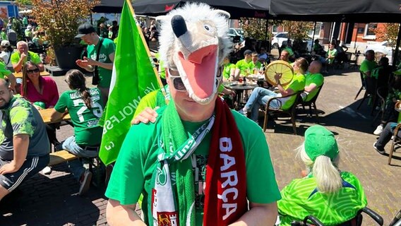 Ein Fan des VfL Wolfsburg trägt eine Kopfbedeckung, die wie ein Plüsch-Wolf aussieht. © NDR 