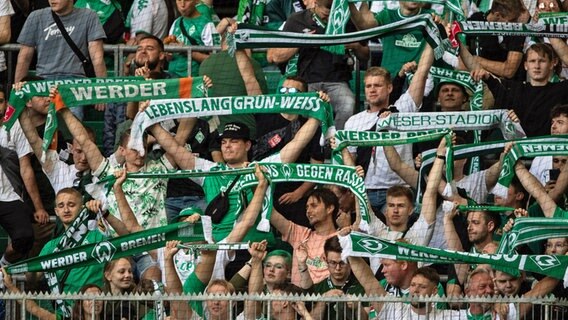 Fans von Werder Bremen stehen mit ihren Schals auf der Tribüne in Wolfsburg. © Swen Pförtner/dpa 