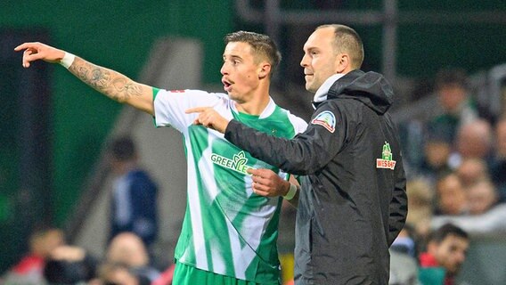 Werder Bremens Marco Friedl (l.) zeigt Trainer Ole Werner etwas. © IMAGO / Sven Simon 