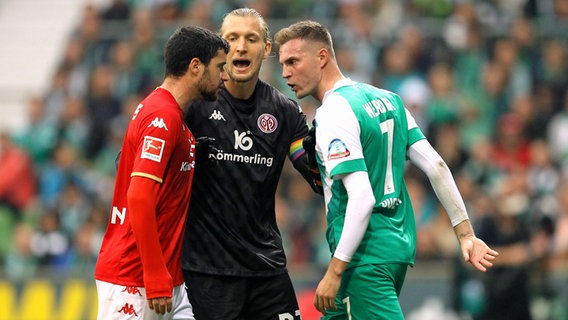 Mainz-Keeper Robin Zentner (M.), versucht zwischen Bremens Marvin Ducksch (r.) und dem Mainzer Aaaron Martin zu schlichten. © IMAGO / Claus Bergmann 